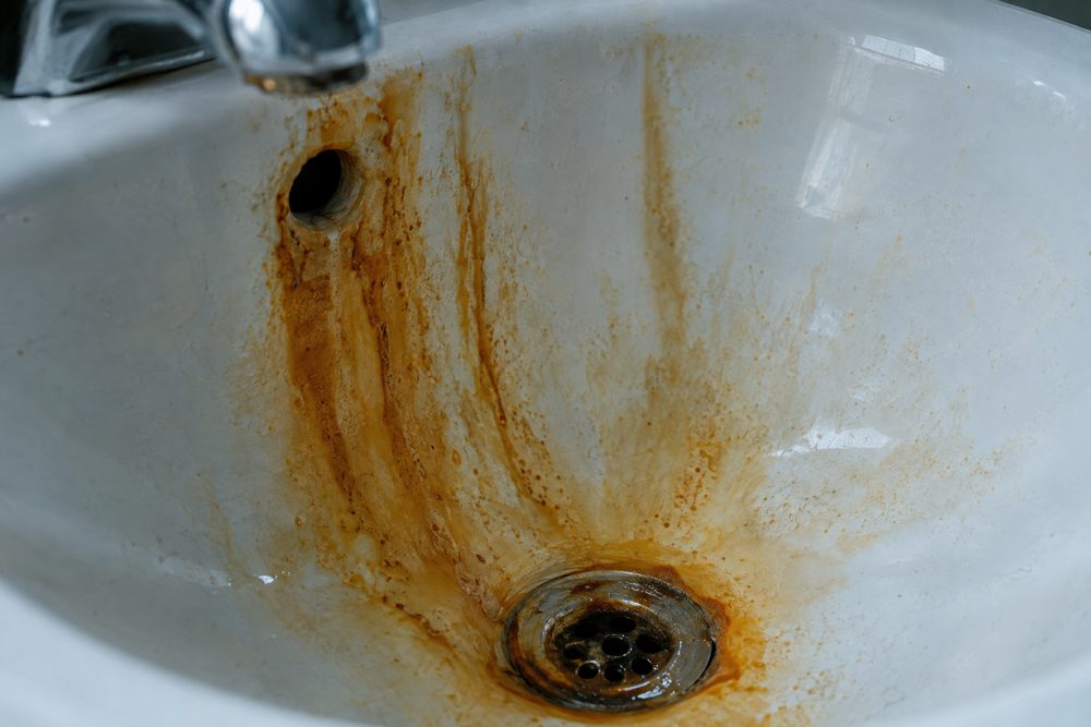 Orange iron and rust staining in a white sink basin